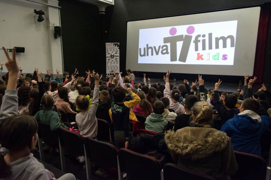 U bioskopskoj salim na platnu je logo uhvati film kids festivala, svetla su upaljena, deca fotografisana sa leđa u publici, mnogi od njih drže podignutu ruku. U daljini se nazire Marijana Ramić Vulin koja je nakon filmova vodila razgovor sa decom.